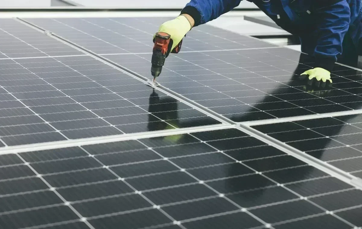 Technician cleaning and inspecting solar panels on a sunny roof
